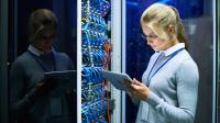 Kvinde står med IPad foran teknik i datacenter